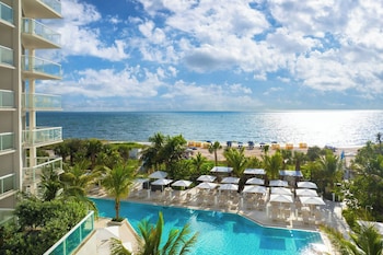 Un resort con piscina, sombrillas de playa y vista al océano.