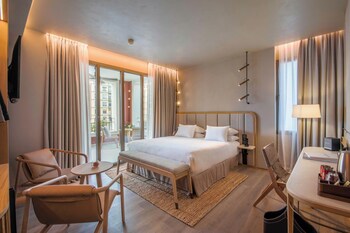 A modern hotel room with a sofa, a round table, a lamp, and a TV.