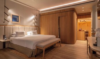 A modern hotel room with a sofa, a round table, a lamp, and a TV.
