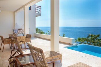 Relax by the pool surrounded by lush gardens and a mosaic wall.