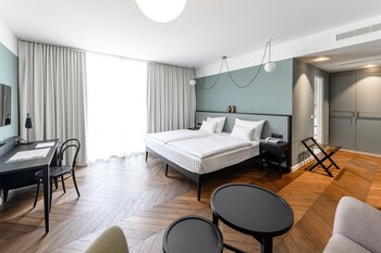 Un couloir moderne, carrelé, avec une porte en verre donnant sur une pièce.