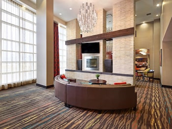 A modern lobby with a curved seating area, a fireplace, and a dining area in the background.