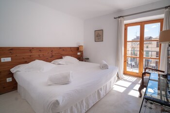 Un dormitorio con una cama grande, un televisor y vistas a la playa a través de una ventana.