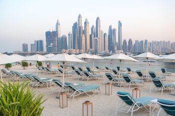 A resort with a large pool, beach area, and views of a city skyline.