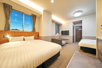 Three beds with white linens, a large window, and air conditioning for a comfortable stay.