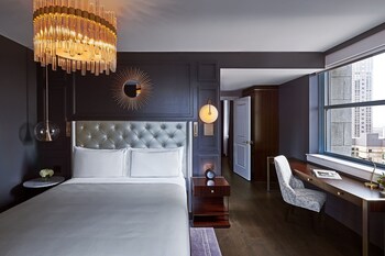A spacious lobby with a plush teal sofa, a round coffee table, and a large chandelier.