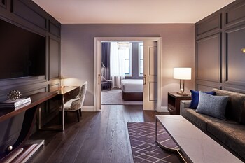 A spacious lobby with a plush teal sofa, a round coffee table, and a large chandelier.