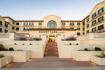 Un hotel Courtyard by Marriott con asientos al aire libre, una chimenea y macetas con plantas.