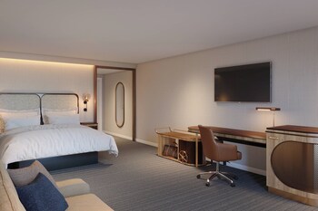 Experience the classic charm of this hotel, featuring a flat roof and arched entrance, surrounded by a beautifully maintained patio with outdoor seating.
