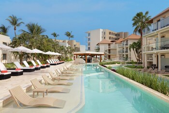 A beachfront hotel with thatched umbrellas, sun loungers, and a pool area.