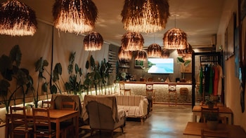En mysig restaurang med trämöbler, hängande lampor och en tv-skärm som visar en strandvy.