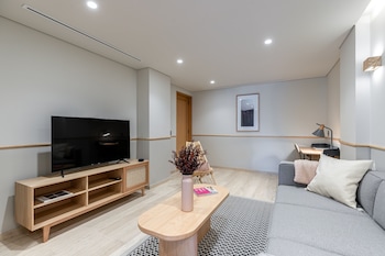 Een moderne slaapkamer met een groot bed, een nachtkastje, een lamp en uitzicht op de stad door grote ramen.