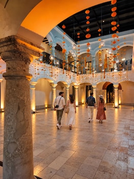 A spacious atrium with multiple arches, a central staircase, and a balcony with a wrought iron railing.