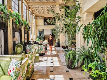 Un lobby de hotel lujoso con techo ornamentado, asientos elegantes y un área de comedor central.