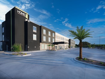 A swimming pool with a view of a modern building and a palm tree.