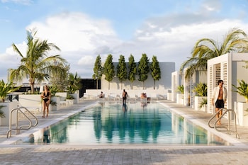 Et moderne poolområde med klart vand, liggestole og plantekasser.