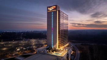 Un moderno vestíbulo de hotel con un mostrador de recepción central, una lámpara de araña grande y un suelo reflectante.