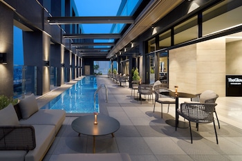 Ein moderner Poolbereich im Freien mit einem überdachten Pool, Liegebereichen und einer Bar.