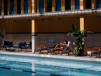 A large indoor swimming pool with multiple lanes, surrounded by balconies with white railings and seating areas.
