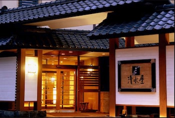 A traditional Japanese garden with a wooden structure, bamboo fence, and a koi pond.