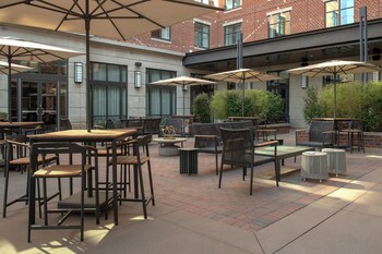 A multi-story hotel with a brick facade, large windows, and outdoor seating area.