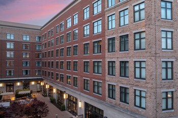 Un hôtel à plusieurs étages doté d’une cour intérieure, de grandes fenêtres et d’une façade en briques.