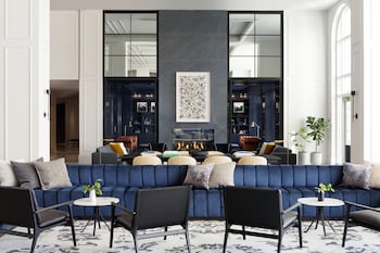 A modern bar area with a long counter, multiple bar stools, and hanging pendant lights.