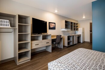 Un hôtel moderne avec un toit plat, une enseigne indiquant « Woodspring Suites » et une plaque avec l’adresse « 3090, boulevard Lake Eastbrook ».