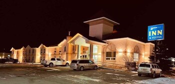Un hall d’accueil d’hôtel avec un comptoir de réception, une enseigne indiquant l’hôtel Aurora Park Inn & Suites, et un escalier menant aux autres parties du bâtiment.