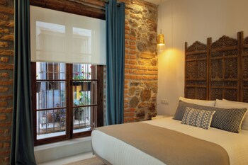 Una habitación con pared de ladrillo, muebles de madera, un candelabro, una planta en maceta y un sofá azul.