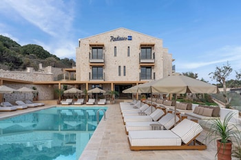 Relax by the ocean with a clear view of the distant mountains, surrounded by lounge chairs and sun umbrellas.
