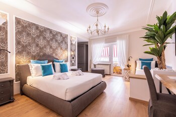 Habitación de hotel con cama, escritorio, televisor, planta grande y bandeja de desayuno.