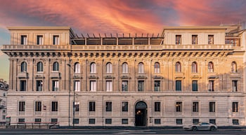 A large, historic building with classical architecture, featuring multiple stories, arched windows, and a prominent entrance.