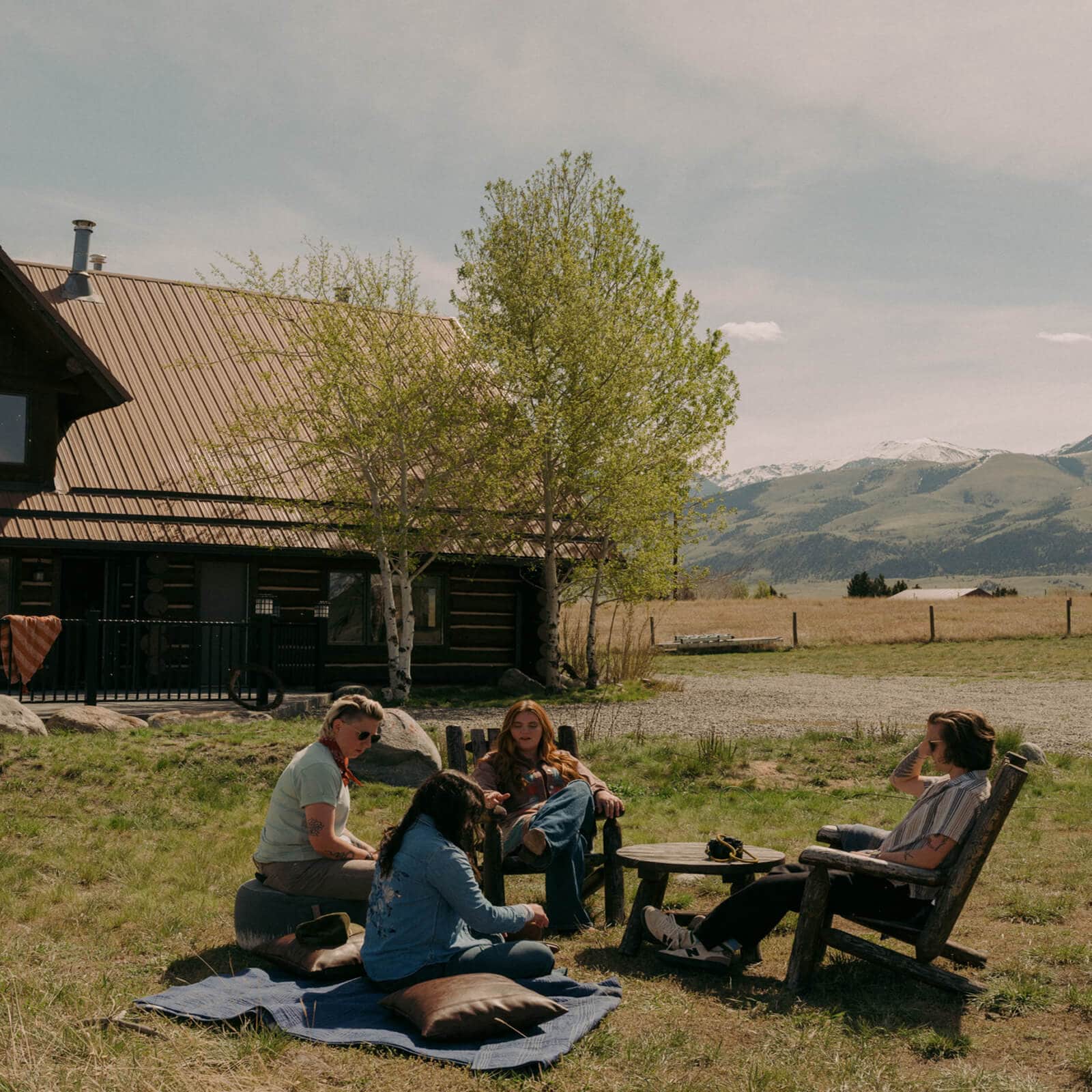 People relaxing outside a rustic cabin with mountain views. 