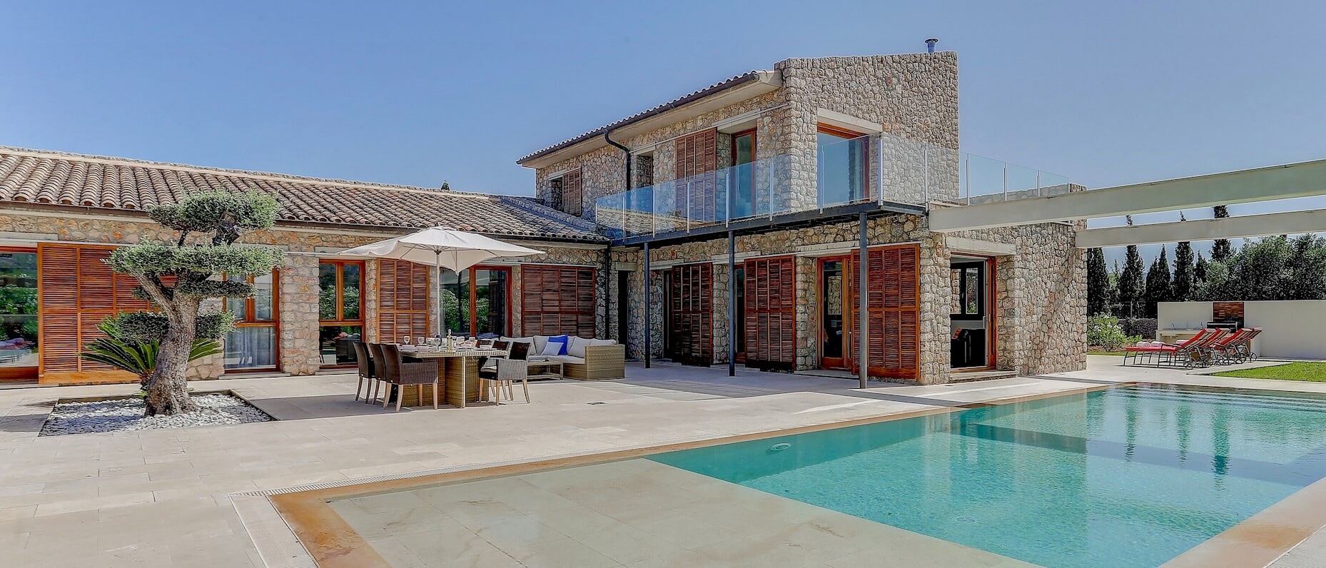 Une maison de vacances entourée de sapins avec un bain à remous et un brasero à l’extérieur