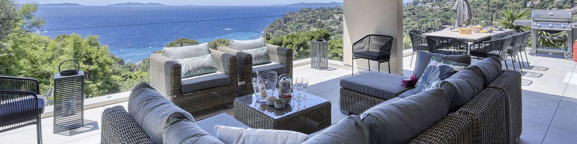 Ein Patio mit Esstisch und Blick auf das Wasser in tropischer Umgebung.