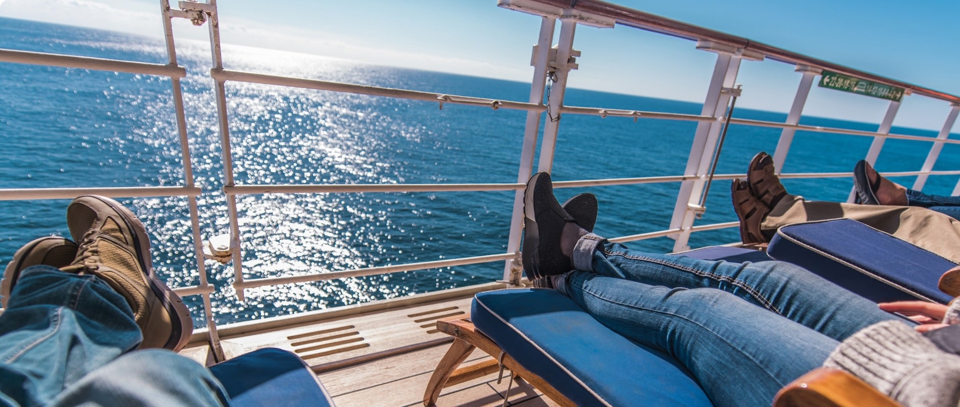 Passengers recline on deck chairs as they take in ocean views aboard a cruise ship.