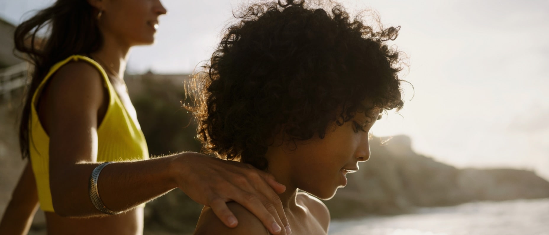 A woman and child head into the water for a swim at a sunny beach