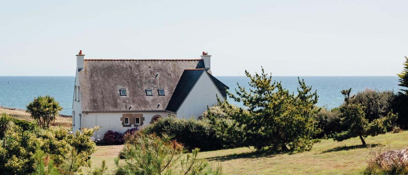 Une maison charmante perchée sur une colline verdoyante avec vue sur l’océan.