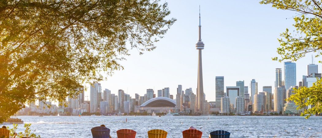 People sitting in colorful deckchairs looking out at the view of the Toronto skyline.