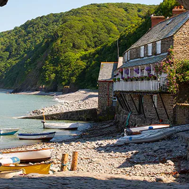 A stone cottage and small boats sit along a peaceful cove framed by a rustic archway and green hills.
