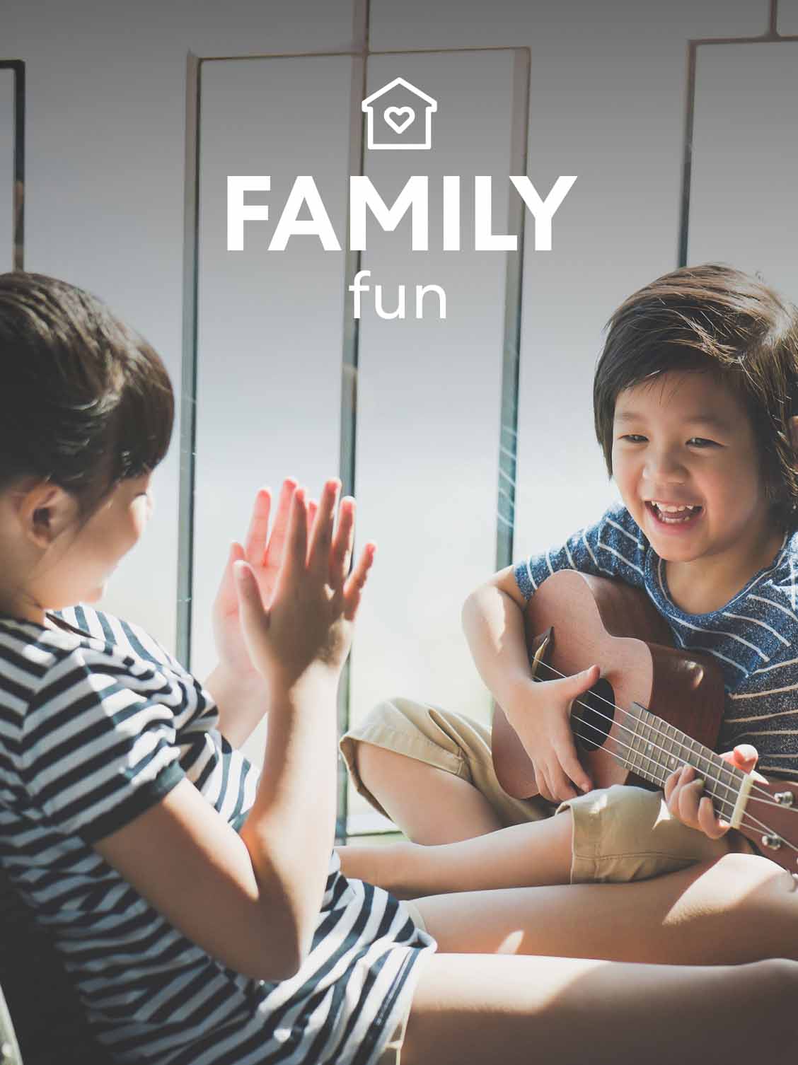 Two children are sitting and having fun. One child is playing the guitar. A superimposed title reads: Family fun.