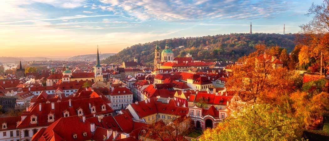 Aerial view of Prague, Czech Republic in the Fall. Trees with orange colored leafs hover in the foreground.