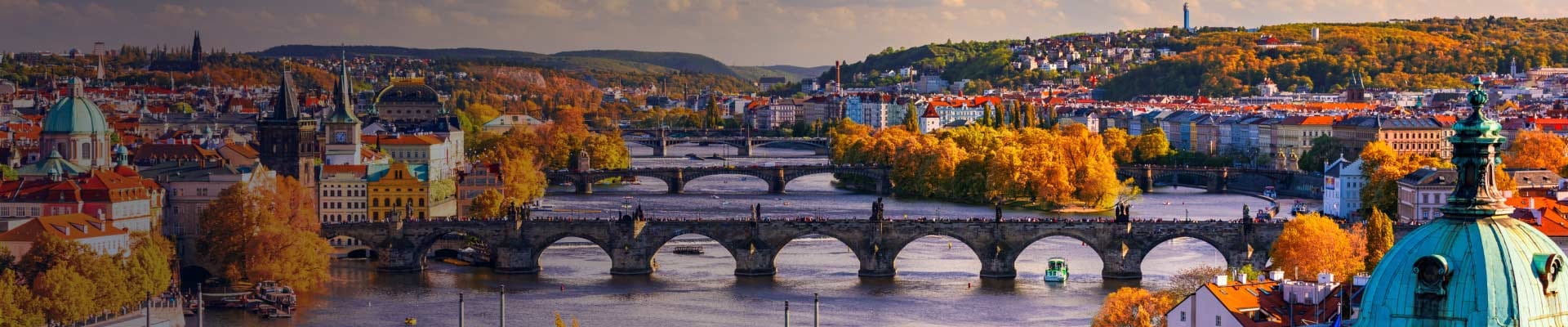 Aerial view of Prague, Czech Republic in the Fall. Trees with orange colored leaves line either side of the Vltava River.