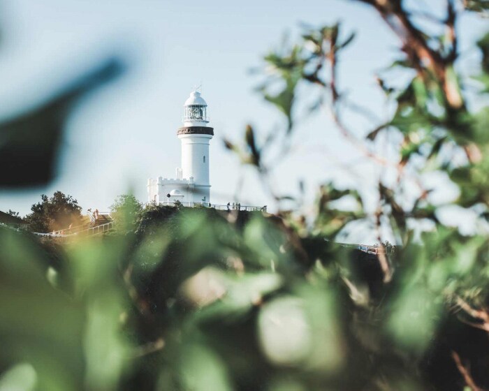 View of Cape Byron Lighthouse in the distance looking through the leaves of a tree.