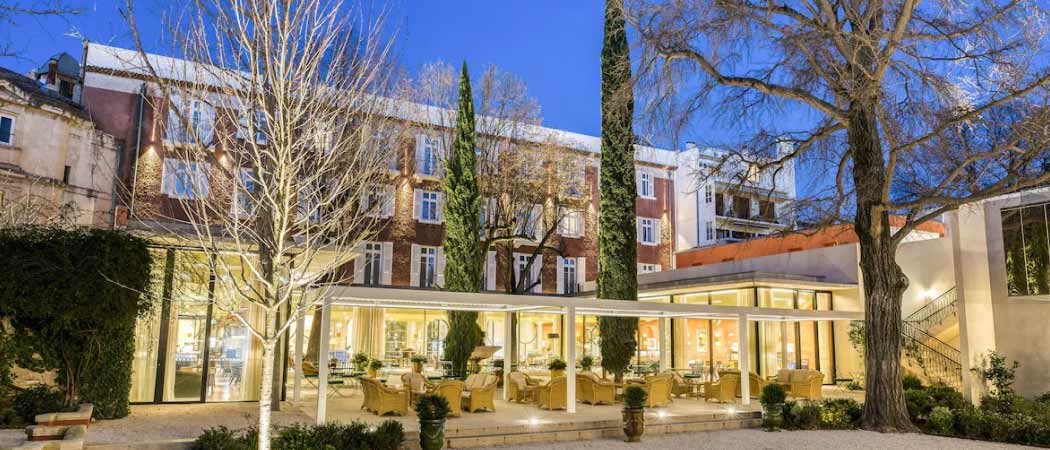 Exterior view of a garden courtyard with yellow armchairs at the Hotel Maison Albar L’ Imperator. 