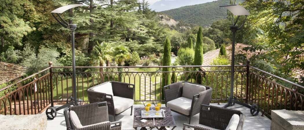 An outdoor setting of a table and chairs sits on a balcony overlooking a lush, verdant backdrop at the Château de Rielle.