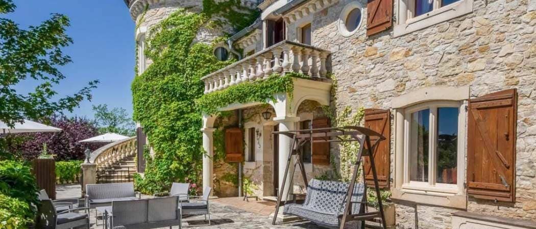 Exterior view of a the stone facade covered in greenery at the Château Camelot in Cambayrac.