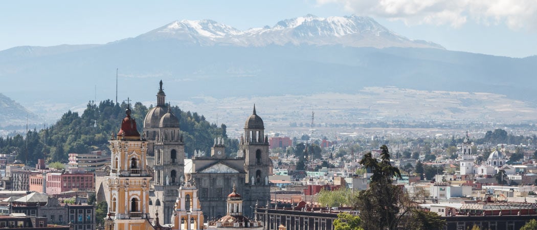 Aerial view of the city of Toluca. A snow-capped mountain is in the far distance.