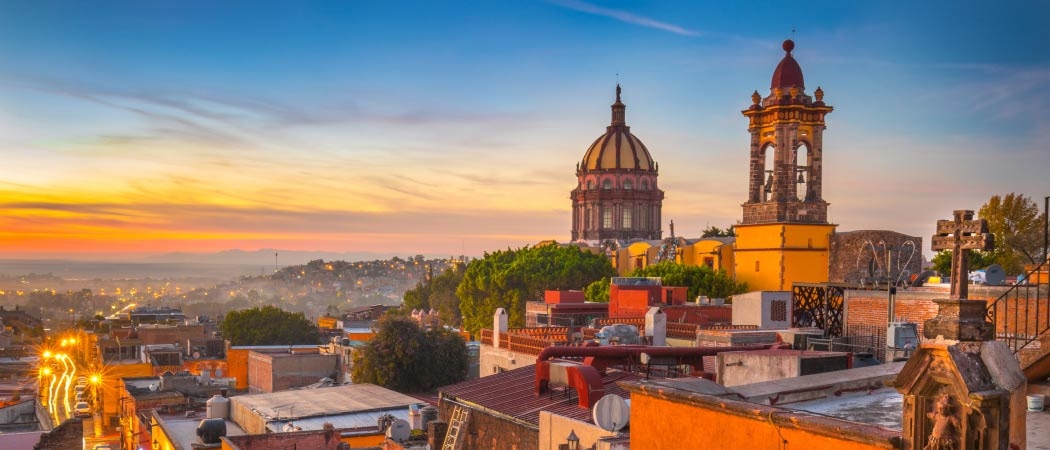 The sun sets over the rooftops of San Miguel de Allende casting an orange glow across the city.